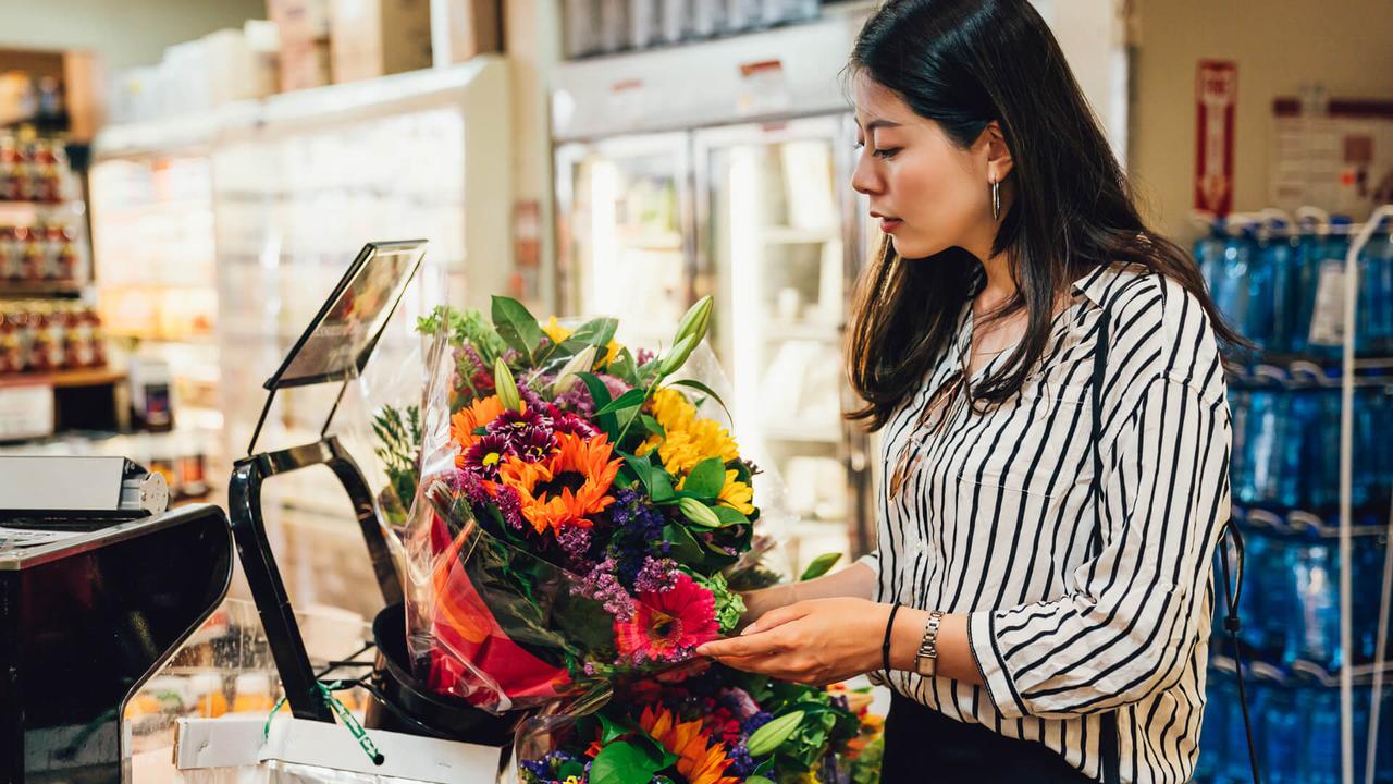 Young asian woman holding beautiful fresh blossom colorful flowers in supermarket.