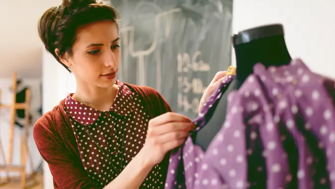 Young fashion designer is preparing a new dress on the female tailor dummy.