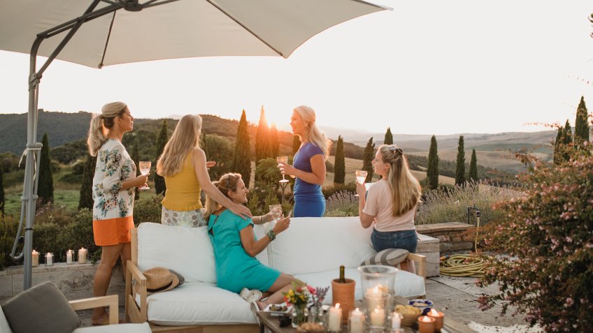 Small group of women are watching the sunset from the garden of their villa on holiday.