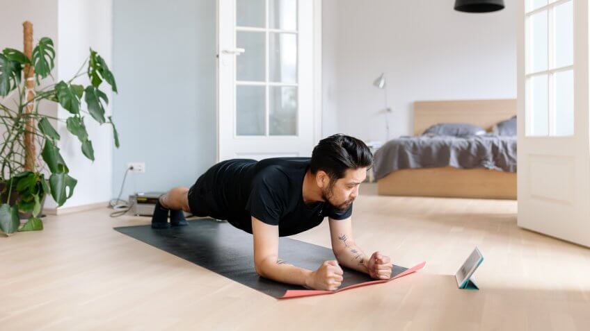 Photo series of a japanese man working out at home, watching youtube videos and learning the exercises.