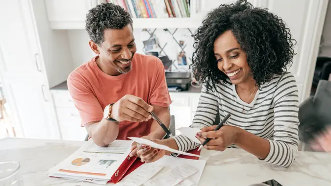 Couple in the kitchen with receipts and laptop.