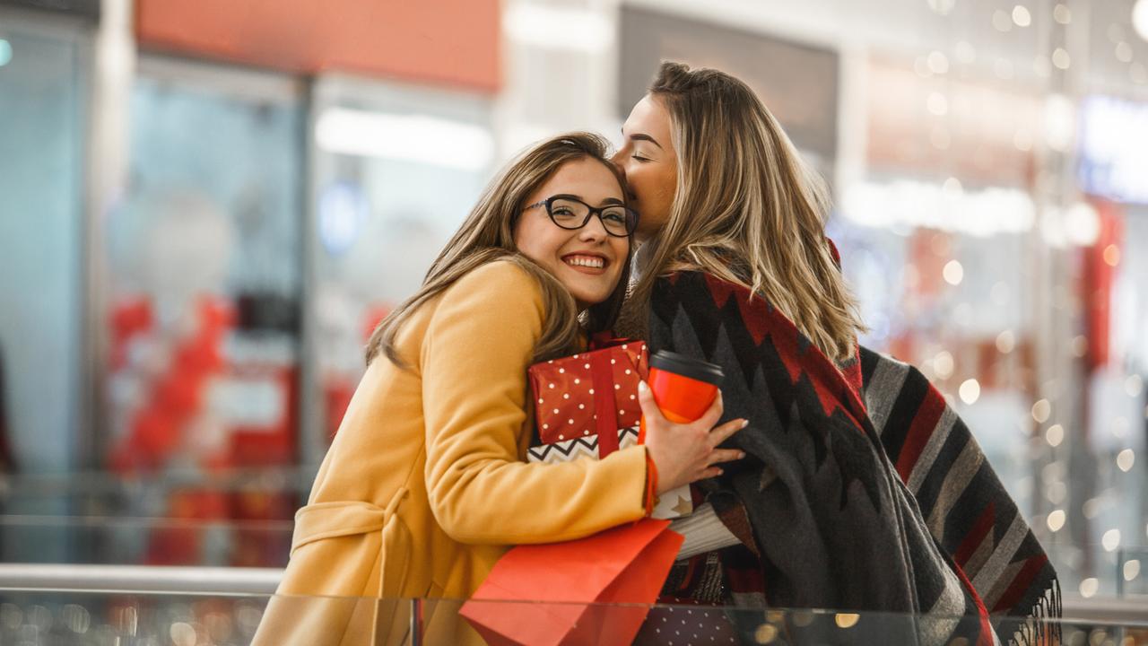 Beautiful young women are hugging and sharing presents after shopping.