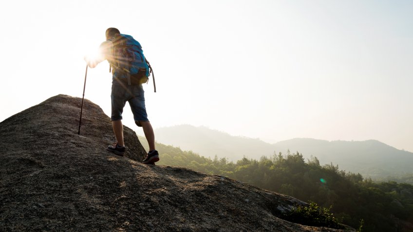 Male backpacker walking on mountain peak.