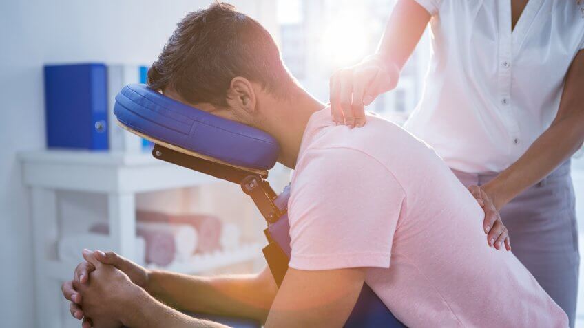 Physiotherapist giving back massage to a patient in clinic.