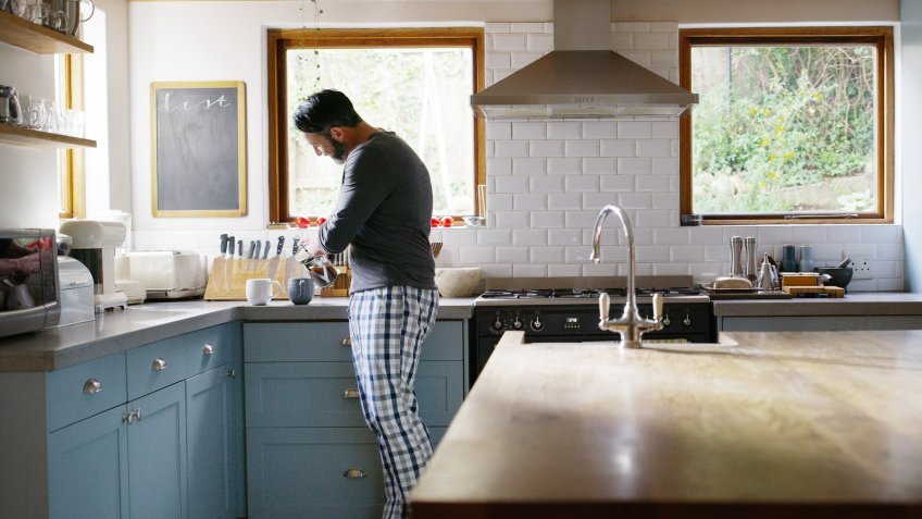 Shot of a man making two cups of coffee in the kitchen at home.