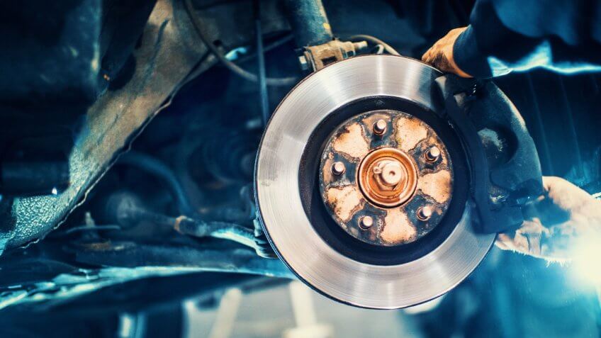 Closeup of unrecognizable mechanic replacing car brake pads.