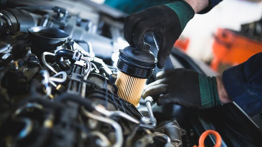 Close up hands of unrecognizable mechanic doing car service and maintenance.