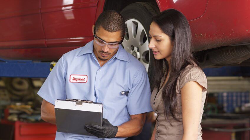 Mechanic in auto repair shop works with customer.