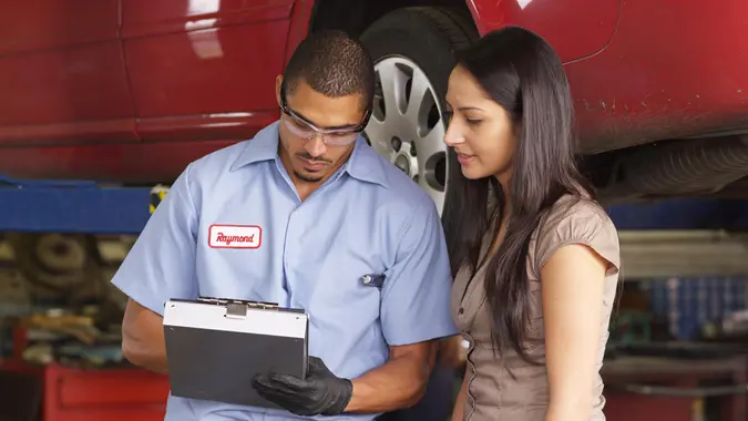 Mechanic in auto repair shop works with customer.