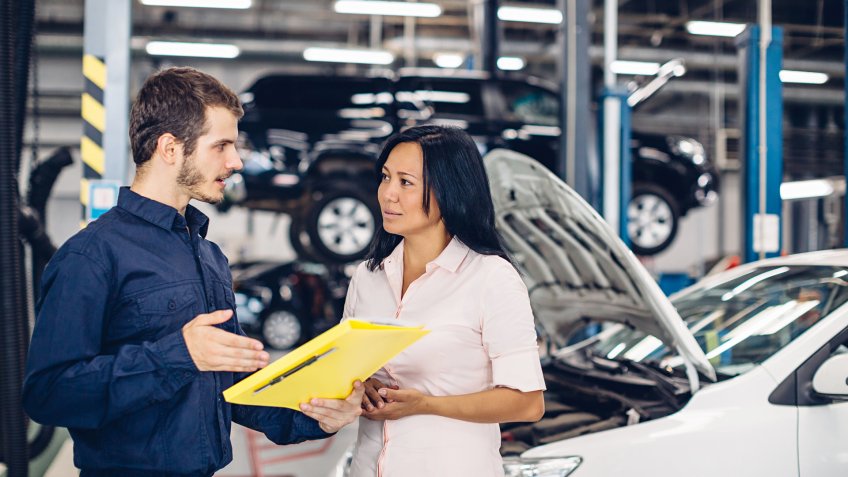 mechanic speaking with female customer in garage