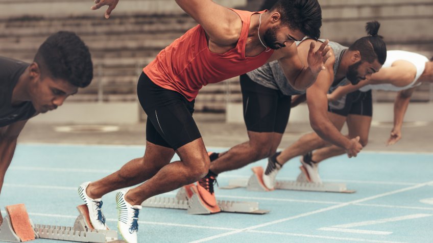 Runners using starting blocks to start the race on running track.