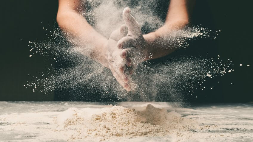 Clap hands of baker with flour in restaurant kitchen.