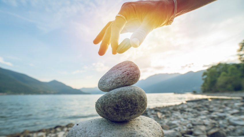 Detail of person stacking rocks by the lake, shot in Ticino Canton, Switzerland.