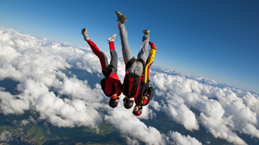 Skydivers plunge through lofty skies.