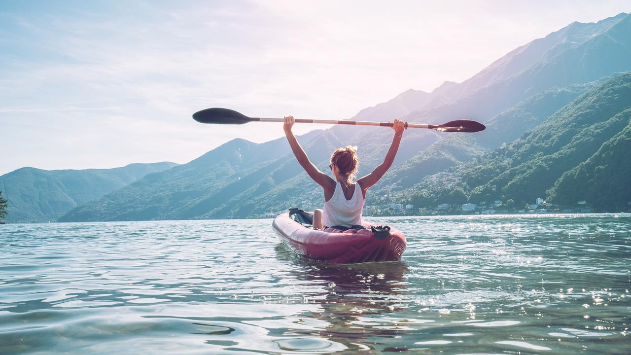 View of a young woman canoeing on beautiful mountain lake in Switzerland.
