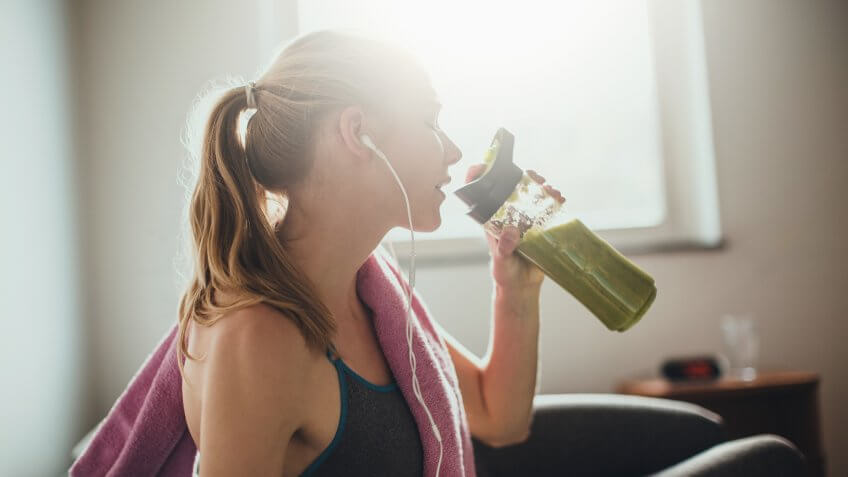 Young woman getting having her green smoothie after training.