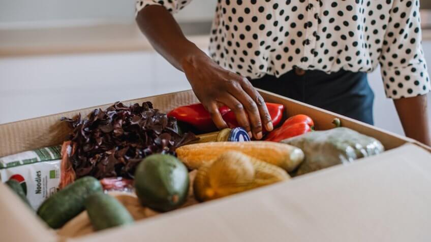 African woman opening parcel with meal kit.