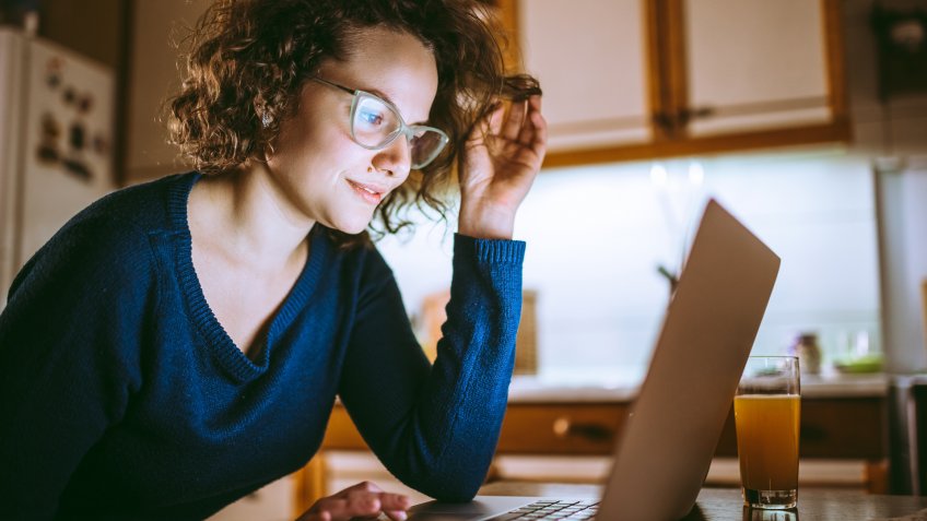 Young beautiful woman looking at the screen of a laptop and smiling.
