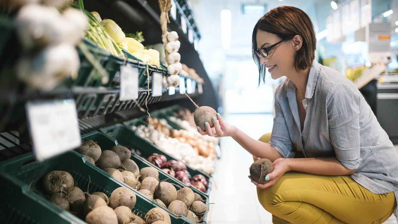 Attractive brunette woman choosing lettuce to buy in a supermarket.