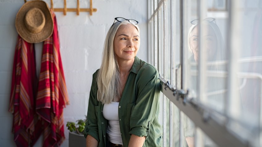 Smiling mature woman looking outside window.