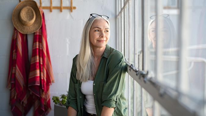 Smiling mature woman looking outside window.