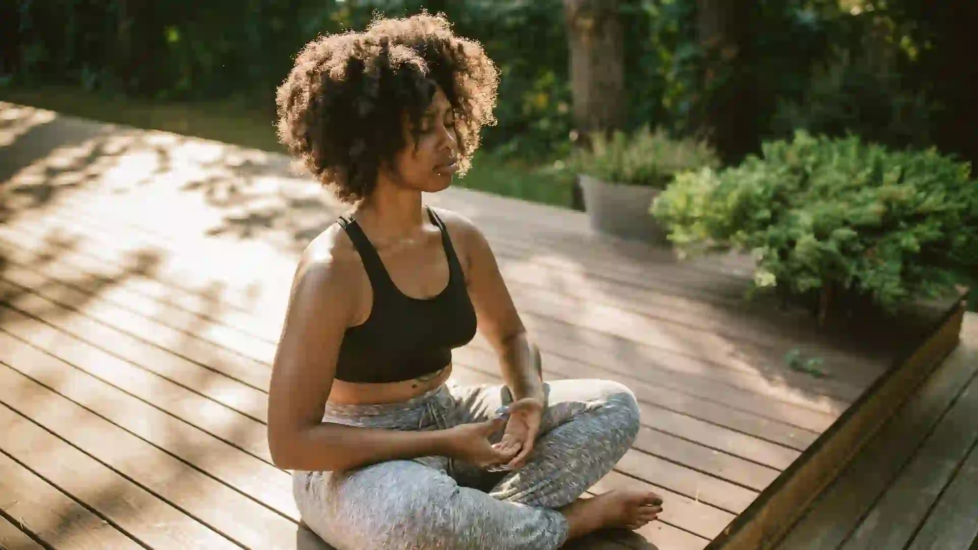 Young woman practicing yoga outdoors on porch, she enjoy in summer sun and meditation.