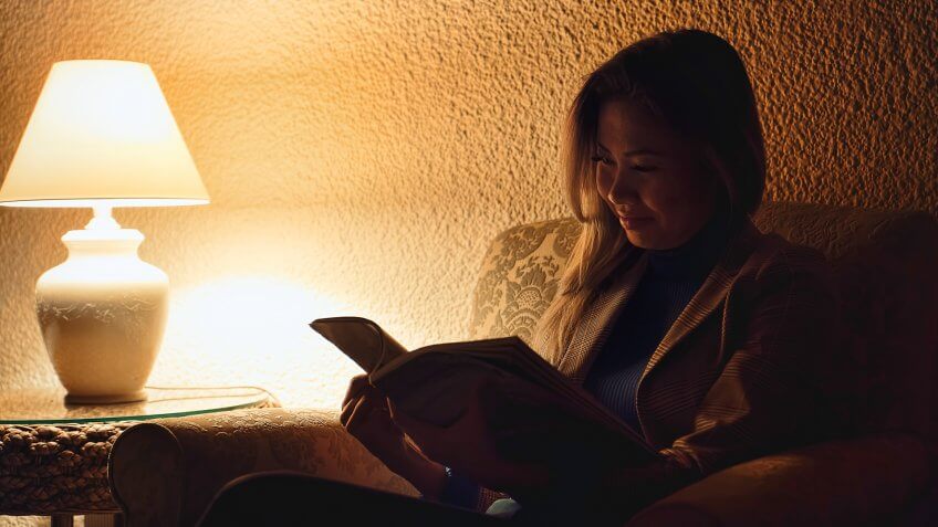 An Asian woman is reading a book in hotel lobby.