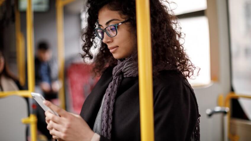 Young woman traveling by bus and using smart phone.