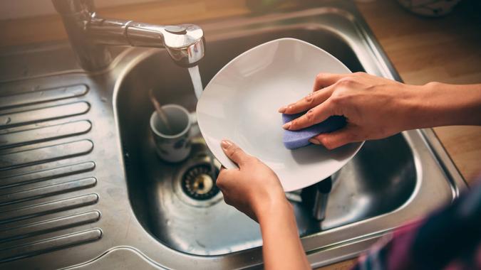 Cute lovely woman standing and washing dishes.