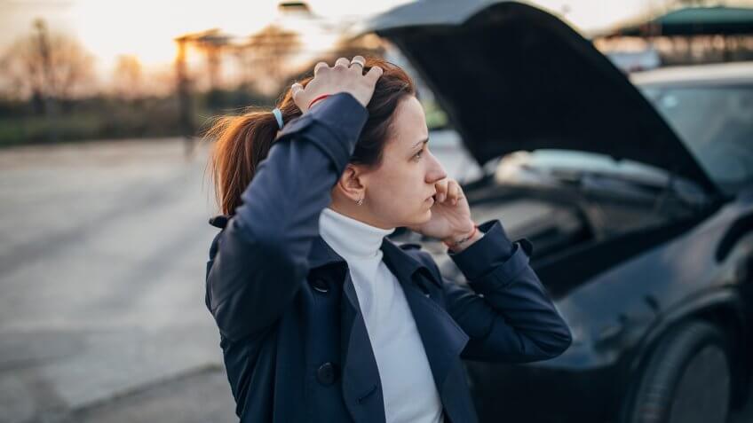 Young, stressed woman is calling emergency service to help her with a broken car.