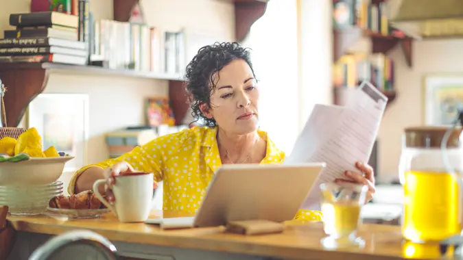 Mature woman is reviewing her finances at home.