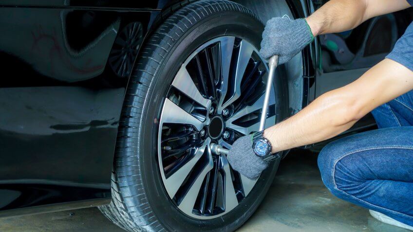 Car mechanic using tools to remove the wheel nuts to check and repair in the car repair center.