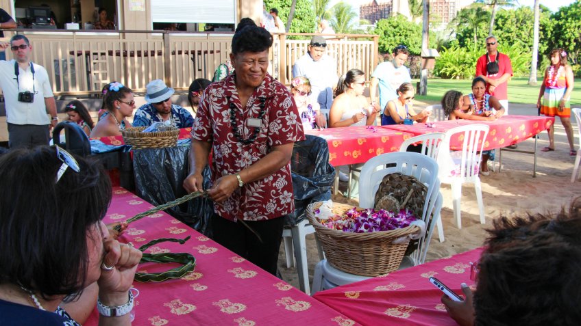 A demonstration of the art of making Hawaiian Lei from ti leaves and orchid flowers, Oahu, Hawaii.