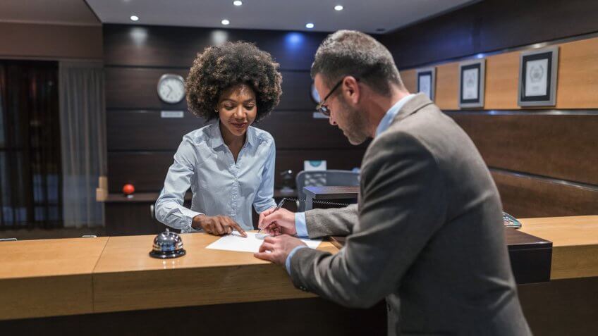 Mid-thirties businessman arriving at the hotel and filling in registration documents.