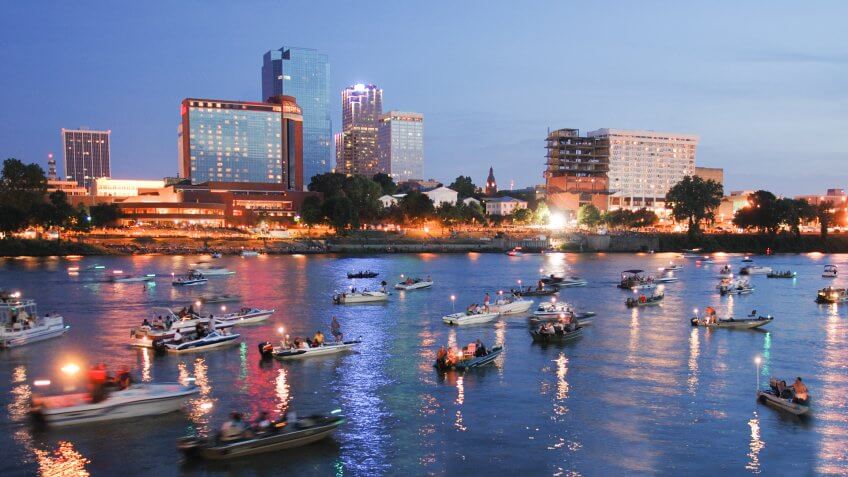 "Skyline of Little Rock, Arkansas, with Arkansas River full of boats in foreground.