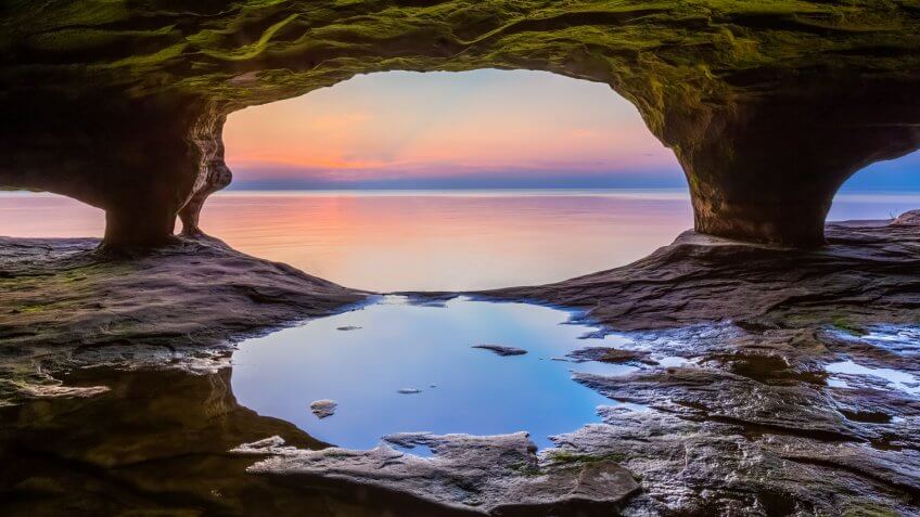 A colorful sunset sky over Lake Superior is photographed from within a sea cave on Michigan's northern coast near Pictured Rocks National Lakeshore.