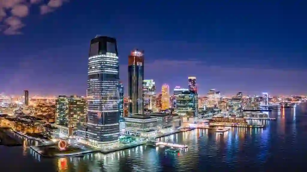 Aerial panorama of Jersey City skyline at night.