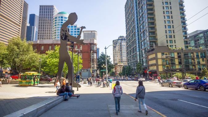 Seattle, Washington, USA - July 2,2017 : People walking on a sidewalk in front of the Seattle Art Museum, which have the hammering man and a skyscraper in the background, Washington, USA.