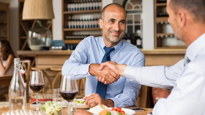 Business people shaking hands during lunch.
