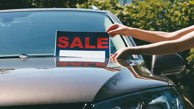 Closeup of a car's front windshield with a "for sale" sign.