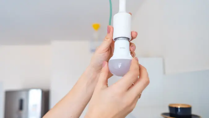 Female hand unscrew a light bulb.