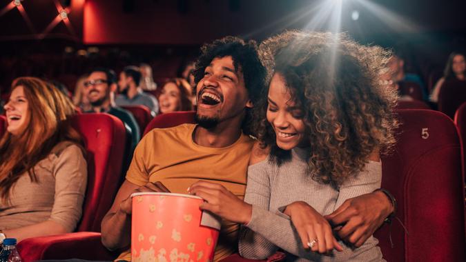 Joyful young people hugging and eating popcorn art the cinema.