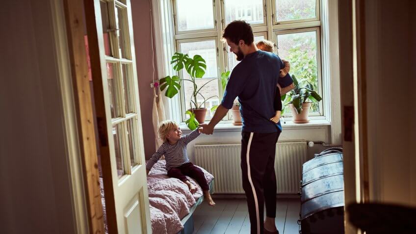 Full length shot of a young man trying to get his children ready in the morning.