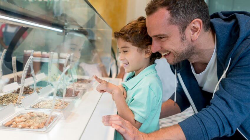 Happy father and son at the ice cream shop choosing the toppings for their sundae - lifestyle concepts.
