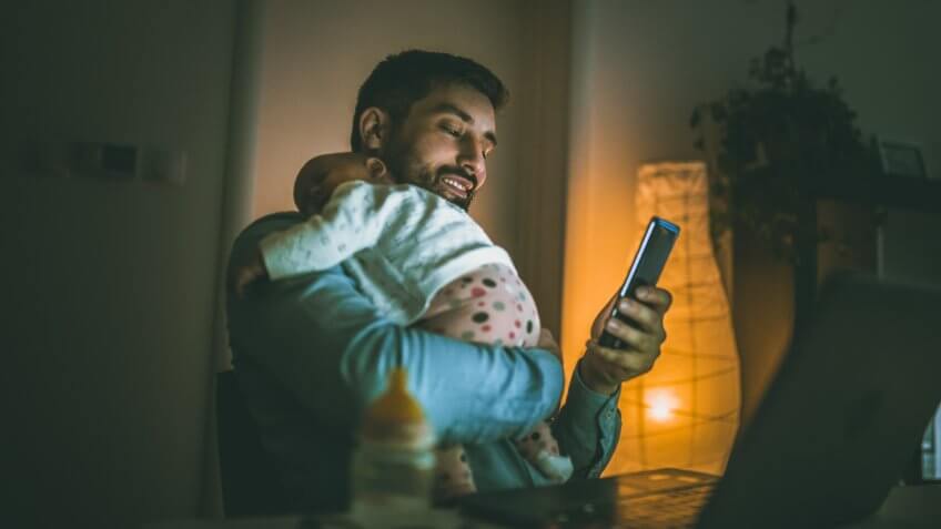 Young father working at home with his baby girl.