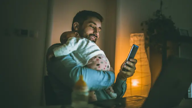 Young father working at home with his baby  girl.