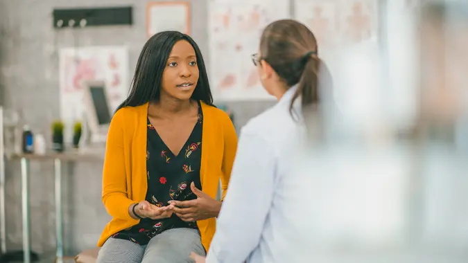 A woman of African descent and her doctor are indoors in a medical clinic.