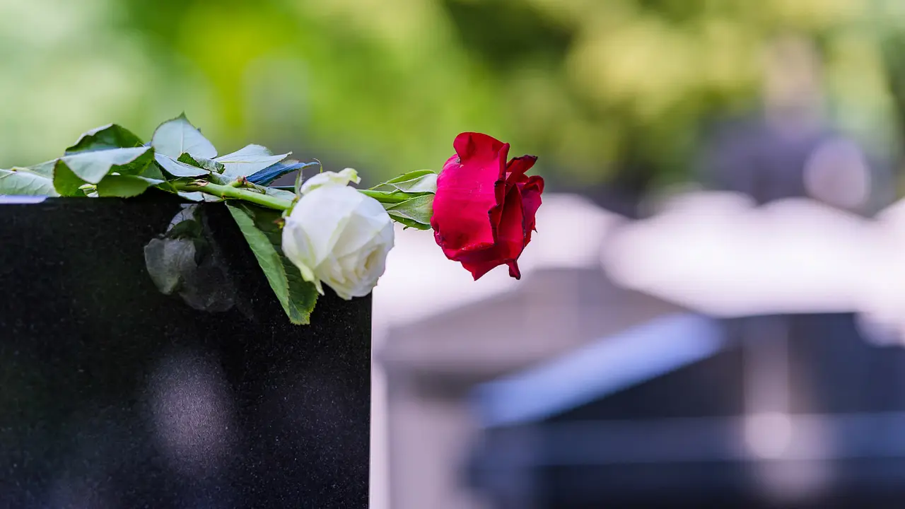 Close View of Headstone In Cemetery With Red Rose Flower.