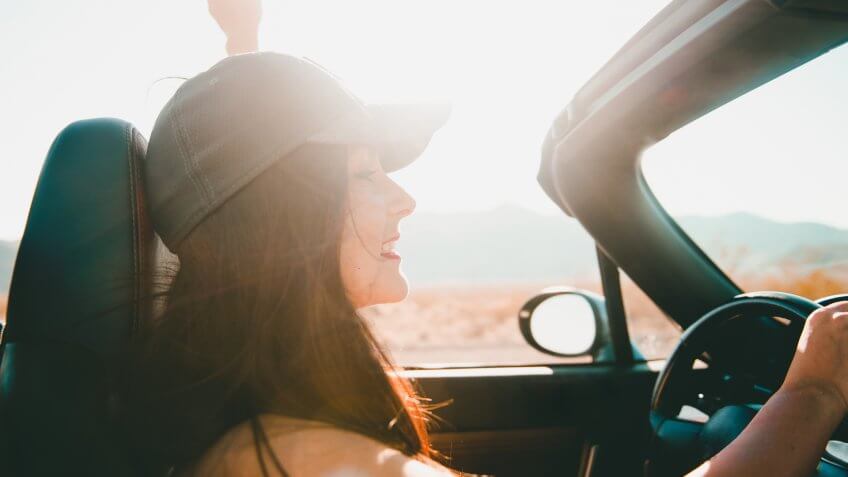 Young beautiful woman driving a convertible car in the desert of Death Valley, California.