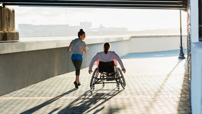 Rear view of two friends exercising along a city waterfront.